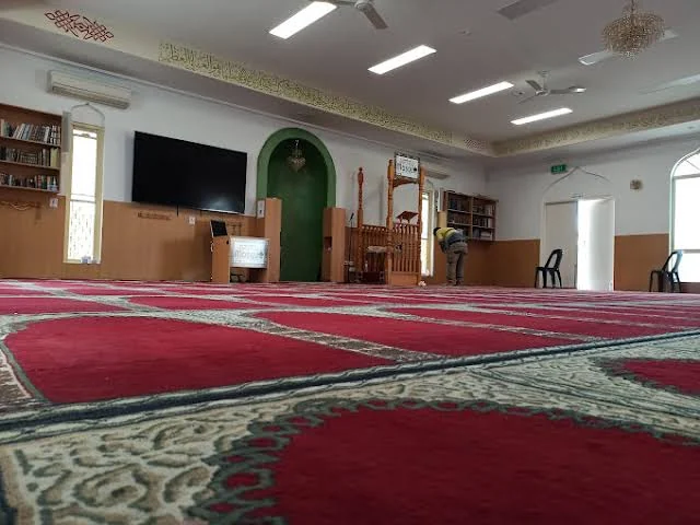 The main prayer hall with red carpet and green mihrab